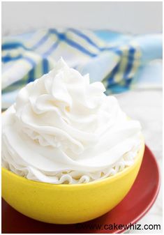 a yellow bowl filled with whipped cream sitting on top of a red and yellow plate