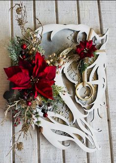 a white clock decorated with red flowers and greenery sitting on a wooden table next to a pair of scissors