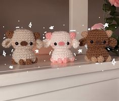 three little stuffed animals sitting on top of a white mantle next to pink flowers and greenery