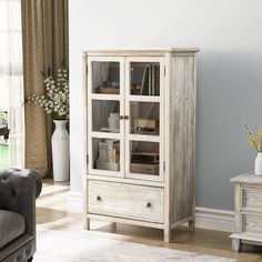 a white cabinet with glass doors in a living room next to a couch and table