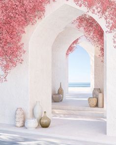 an archway with pink flowers and vases next to it