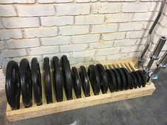 a bunch of black wheels sitting on top of a wooden rack next to a brick wall