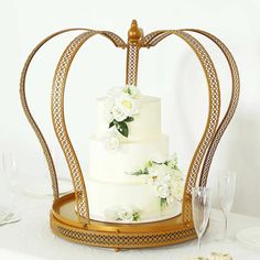 a wedding cake with white flowers on it in a heart - shaped frame, surrounded by wine glasses