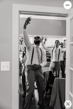 a group of men standing around each other in front of a doorway with their arms up