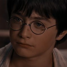 a young boy wearing glasses looking at the camera with an intense look on his face