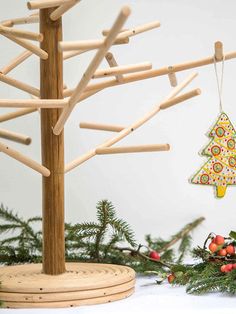 a christmas tree ornament hanging from a twig on top of a wooden stand