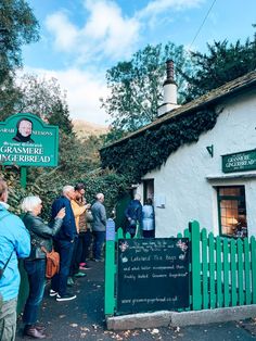 people standing in front of a white building with green trim and a sign that says the grasmere inn bed and breakfast