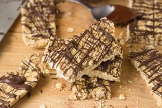 chocolate drizzled on top of peanut butter bars with a knife and spoon in the background