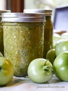 there are many green apples next to some jars with food in them on the table