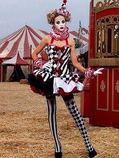 a woman dressed as a clown standing in front of a carnival tent with her hands on her hips