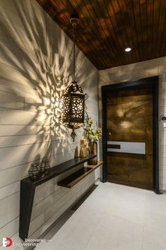 an entryway with a wooden door and light fixture hanging from the ceiling above it