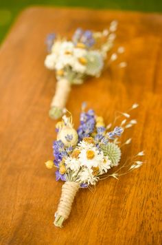 two bouquets of flowers are sitting on a wooden table with green grass and bluebells