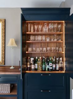 an open cabinet filled with wine glasses and liquor bottles