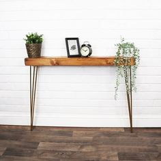 a wooden table with two plants on it and a clock sitting on top of it