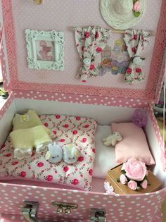 an open pink suitcase with stuffed animals and decorations on the bed in front of it