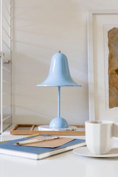 a blue lamp sitting on top of a table next to a cup and saucer