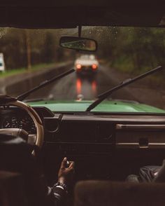 a car driving down a rain soaked road next to a person holding a cell phone