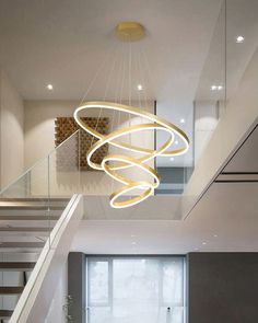 a modern chandelier hanging from the ceiling in a living room next to stairs