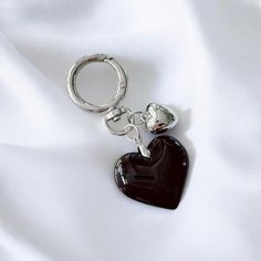 a black heart shaped keychain sitting on top of a white cloth