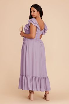 a woman in a purple dress is standing and looking at the back of her dress