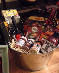 a metal bucket filled with assorted items on top of a wooden table