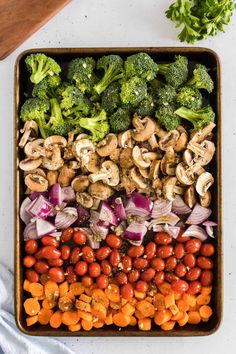 a tray filled with broccoli, tomatoes, mushrooms and other veggies