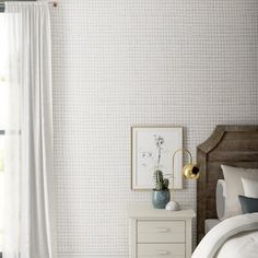 a bedroom with a bed, nightstand and white wallpaper in the corner next to a window