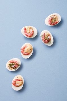 several small pieces of food are arranged in the shape of eggs with shrimp on them