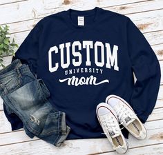 "Custom University Mom Sweatshirt, Cool Cozy University Mom Gift Sweater, Proud Mom Crewneck , standard USA size men's women's available in 6 color ; Black, White, Navy, Sport Grey, Irish Green and Red. This Sweatshirt using USA standard size; S, M, L, XL, 2XL, 3XL. Sweatshirt Spec's Using Direct to Garment (DtG) for quality and durability print. * 8 oz./yd² (US) 13.3 oz./L yd (CA), 50/50 preshrunk cotton/polyester * Classic fit * Air jet yarn for softer feel and reduced pilling * Double-needle stitching at shoulders, armholes, neck, waistband and cuffs * 1x1 rib with spandex for enhanced stretch and recovery Size Chart * SMALL (W 20\" / L 27\" / SLEEVE 33.5\") * MEDIUM (W 22\" / L 28\" / SLEEVE 34.5\") * LARGE (W 24\" / L 29\" / SLEEVE 35.5\") * X-LARGE (W 26\" / L 30\" / SLEEVE  36.5\") Long Sleeve Letter Print Campus T-shirt, Long Sleeve Letter Print T-shirt For Campus, Cotton Campus Tops With Team Name, Relaxed Fit Lettering Tops For Campus, Relaxed Fit Long Sleeve T-shirt For Campus, Long Sleeve Relaxed Fit T-shirt For Campus, Long Sleeve Tops With Lettering For Campus, Varsity Long Sleeve T-shirt With Lettering, University Sweater