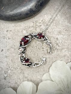 This wire wrapped crescent moon pendant was created using three genuine, faceted red garnet gemstones.  The largest garnet is a 10 x 7mm oval.  The two smaller garnets are 6mm rounds.  All three garnets have a deep reddish-purple coloring, and all are genuine, earth-mined gemstones.  The moon pendant was created with thick, 16 gauge solid sterling silver wire with chaos-style swirling loops and accents to decorate the piece.   About the Pendant:  - One-of-a-kind piece - 100% handmade - Genuine gemstones - Solid sterling silver chain & wire - Safe for daily wear - Suitable for those with metal allergies or sensitivities The pendant is shipped with a matching sterling silver chain or leather necklace (choose below).  Care instructions are included in the package.  The pendant will be profess Moon Jewelry Silver, Moon Crystal Necklace, Cresent Moon Necklace, Wire Wrapped Moon, Crescent Moon Jewelry, Mushroom Jewelry, Crescent Moon Pendant, Moon Crystal, Garnet Necklace