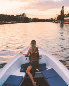 a woman sitting in the back of a boat on top of a body of water