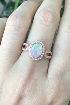 "An Oval Faceted Natural and Genuine Opal set in a bezel setting accented with petite white sapphires handcrafted in your choice of 10k/14k/18k Rose/Yellow Gold or White Gold. This ring makes a lovely engagement/promise/October birthstone/statement ring. Wrapped in a Box ready for gift giving.(r-egt-20) Please note each opal has a unique play of color, if you wish for a certain color in the fire, please let us know and we will try to accommodate your request. View our Instagram video of this Rin Oval Opal Rings With Bezel Setting, Rose Gold Oval Opal Promise Ring, Oval Rose Gold Birthstone Ring With Bezel Setting, Rose Gold Oval Birthstone Promise Ring, Oval Opal Jewelry With Bezel Setting, Dazzling Oval Opal Ring, Oval Rose Gold Birthstone Promise Ring, Oval Rose Gold Birthstone Ring For Anniversary, Oval Bezel Set Jewelry For Anniversary