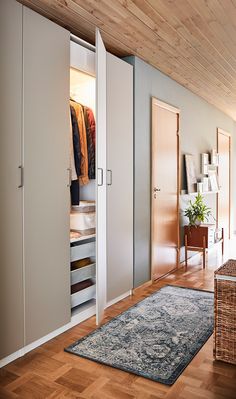 an open closet with clothes on hangers and a rug in front of the door