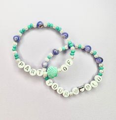 two beaded bracelets with words and seashells are shown on a white surface