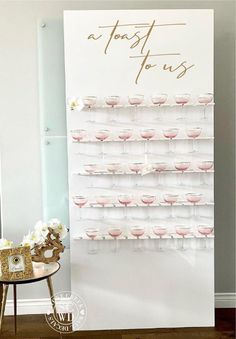 a wine glass display on a white wall next to a small table with flowers in it