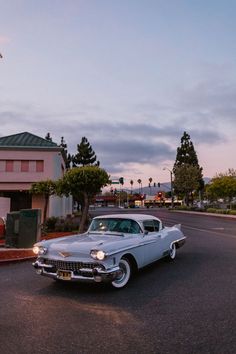 an old car is parked on the side of the road in front of a building