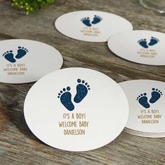 four personalized coasters with baby feet and footprints on them sitting on a wooden table