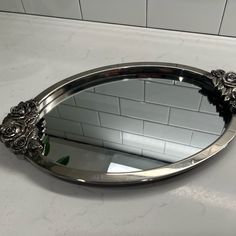 a mirror sitting on top of a counter next to a white tiled wall and floor