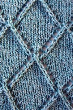 a close up view of a blue knitted cloth with squares and diamonds on it