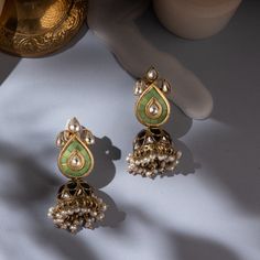 Introducing our Amara Mini Jhumkis – a blend of tradition and modern elegance. These Indian jhumka silver earrings feature pastel green stones in jadau craft on the studs, with a central polki. The jhumki showcases alternate polki and black stones in a captivating jadau style. Crafted in silver, gold-plated for a premium look, these chandi ka jhumka earrings redefine sophistication. Shop online for pearl jhumka earrings with kundan jadau polki design, embracing the allure of chandi ki earrings. Fusion Kundan Jhumkas With Gota Work, Fusion Style Kundan Jhumkas With Gota Work, Festive Fusion Kundan Jhumkas, Green Kundan Bridal Earrings With Cutdana, Green Chandbalis With Cutdana, Green Cutdana Bridal Earrings As Gift, Green Cutdana Chandbalis For Diwali, Green Bridal Earrings With Cutdana As Gift, Green Cutdana Chandbalis