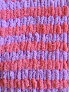 a crocheted blanket with pink and purple stripes