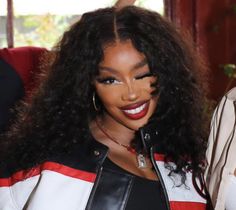 a close up of a person wearing a black and white jacket with long curly hair