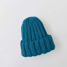 a blue knitted beanie sitting on top of a white surface