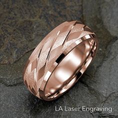 a rose gold wedding band with an intricate design on the outside and inside, sitting on top of a rock