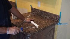 a man is painting a counter top with blue tape