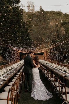 a bride and groom standing in front of a long table