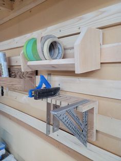 some tools are hanging on the wall with wooden planks and tape dispensers