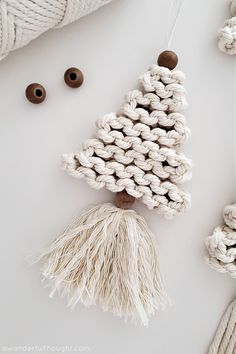 a crochet christmas tree ornament with tassels and buttons next to it