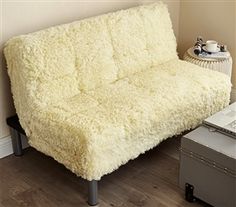 a white futon couch sitting on top of a hard wood floor next to a wall