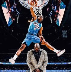 two basketball players jumping up to dunk the ball in front of an arena full of people